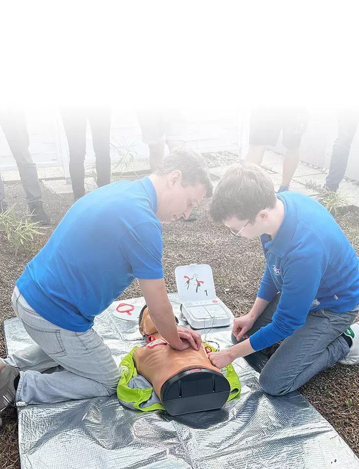 Two ODU employees kneel on the floor and practice chest compressions on a dummy.